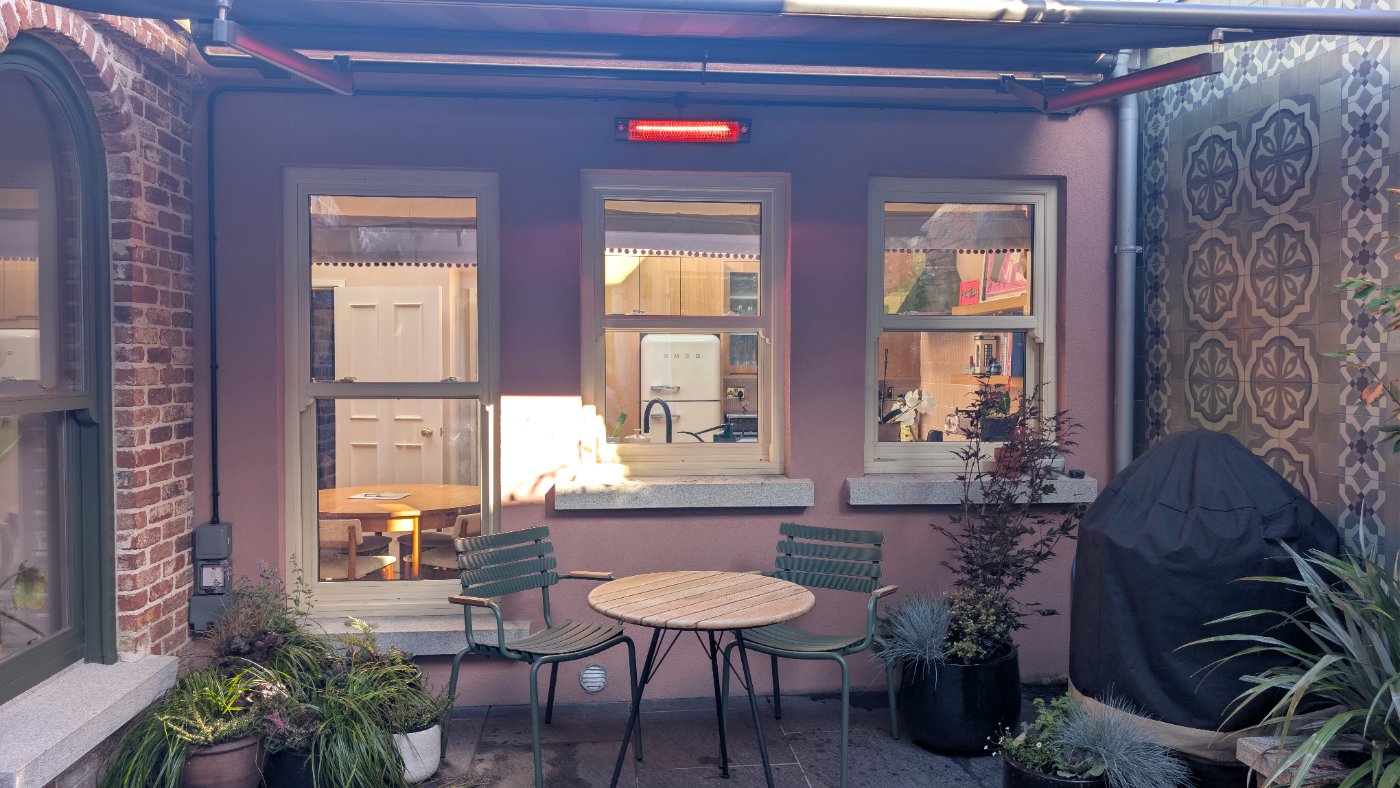 The courtyard under the canopy, with the outdoor heater on, a bistro table and planting