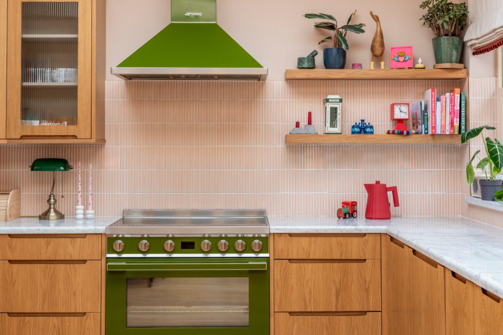Kitchen with a green range, pink tiles and oak shelves